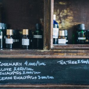 Close-up of essential oil bottles with handwritten labels on a wooden shelf, promoting natural aromatherapy and holistic health.