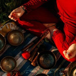 A person meditating outdoors with Tibetan singing bowls, creating a peaceful atmosphere.